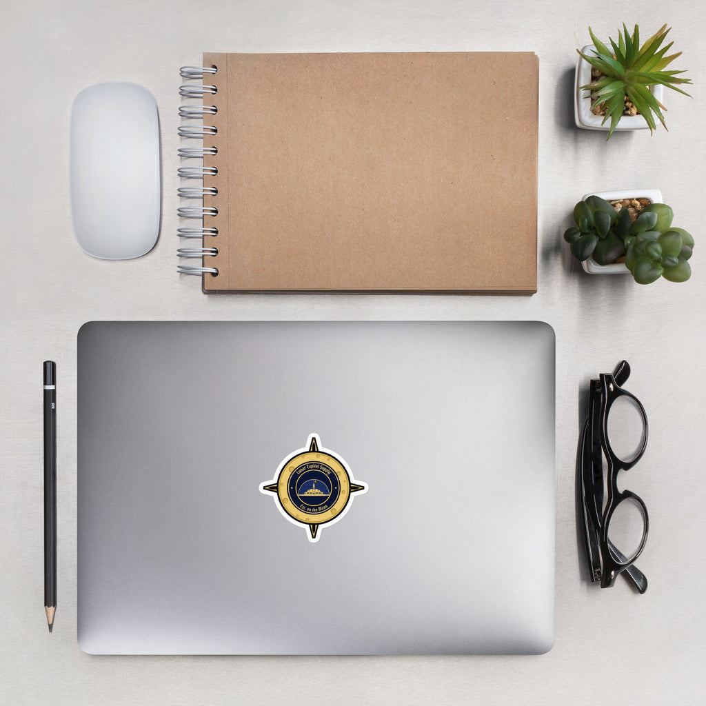 3 inch Lunar Capitol Dome Crest Sticker on a silver laptop lid beside a kraft notebook, mouse and glasses